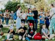 A diverse group of families and children enjoying an outdoor event on a sunny day in a park setting.